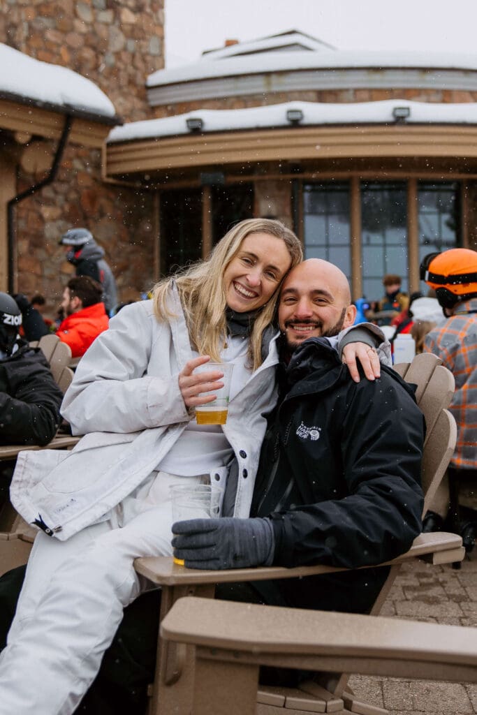 Couple enjoys local craft beers around the fire on their winter elopement day at Snowbasin Ski Resort