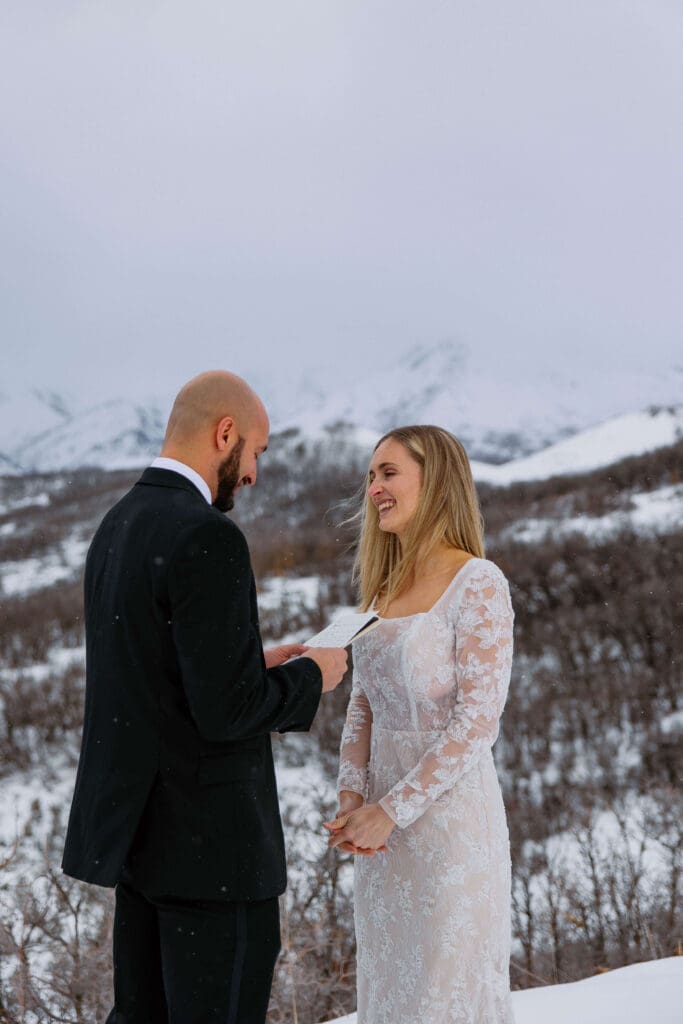 bride and groom read vows at a snowy mountain overlook near Snowbasin Ski Resort in Utah