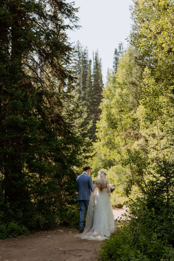 bride and groom walk through the forest