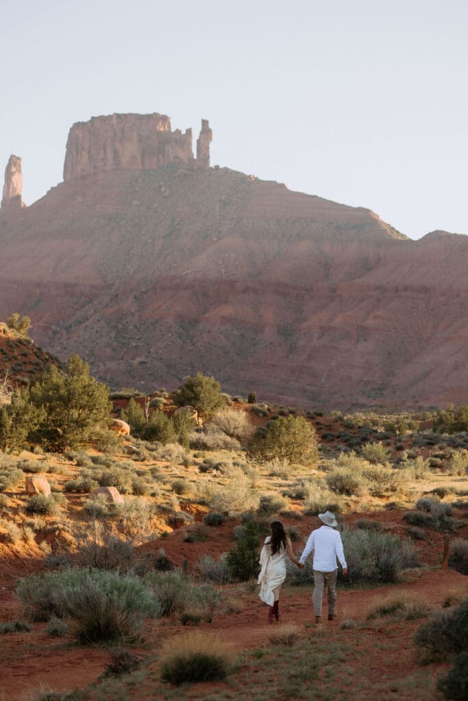 bride and groom walk through desert on elopement day in moab