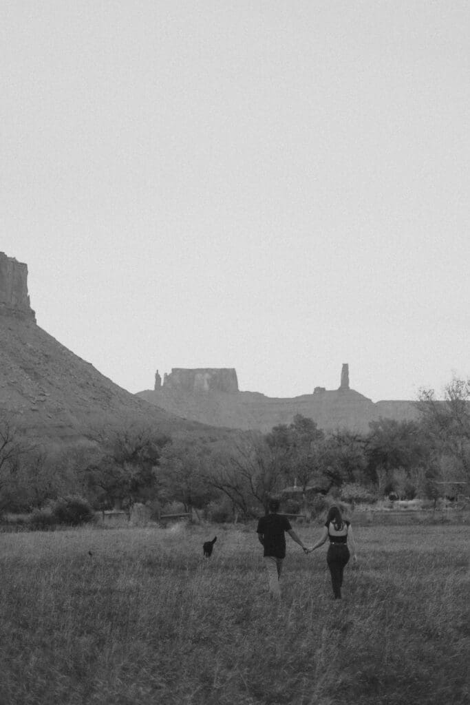 couple walks through moab field with dog