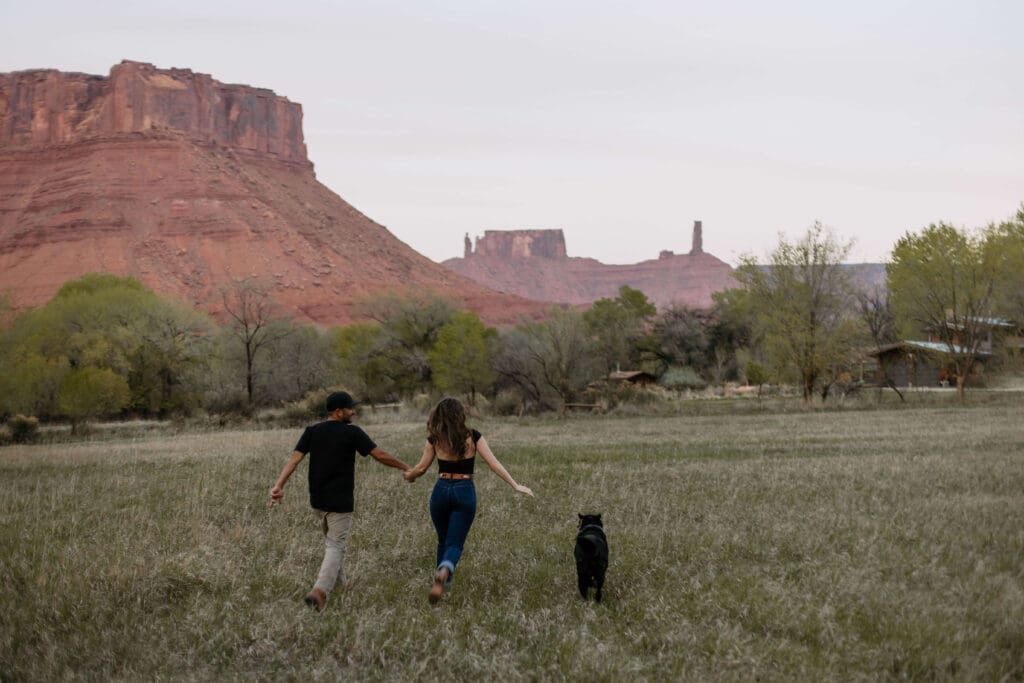 couple runs through backyard with dog in moab