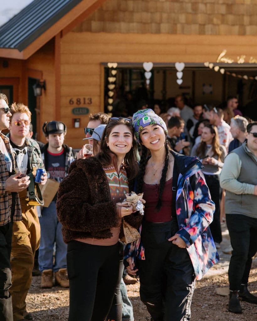 two girls smiling at camera at cabin party while eating chipotle burritos