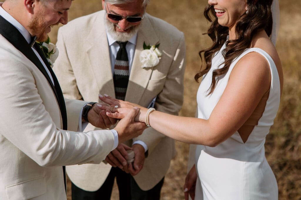 bride and groom exchange rings in the mountains