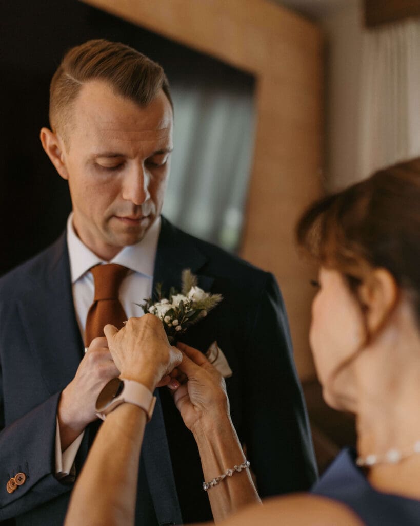 mom puts boutonniere on groom at moab wedding