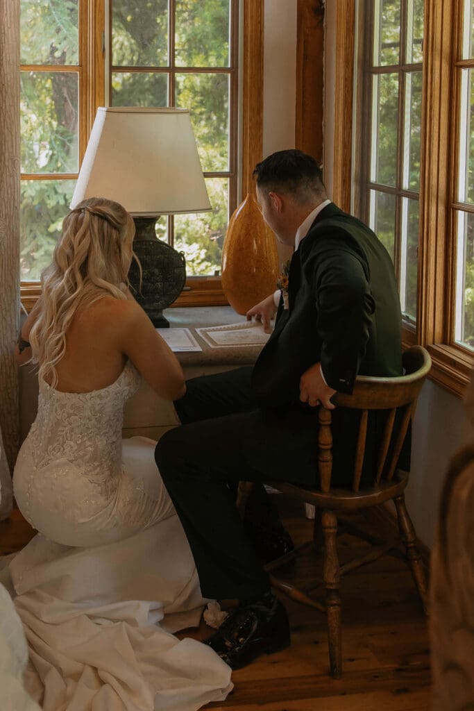 bride and groom sign marriage license at cabin wedding
